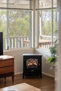 a living room with a fireplace in front of a window at Hillview - Spacious Bushland Haven with Resort Access in Yallingup