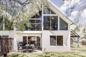 a white house with large windows and a table and chairs at Banksia at Whitesands - Villa 5 Loft-Style Living by the Bay in Dunsborough
