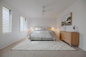 a white bedroom with a bed and a dresser at Luxury at the Cove - Seaside Comfort & Entertainment in Quindalup
