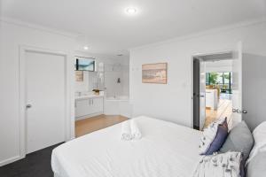 a white bedroom with a bed and a bathroom at Blue Haven Townhouse - Beachside Retreat with Pool Access in Gnarabup