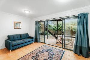 a living room with a blue couch and a sliding glass door at Blue Haven Townhouse - Beachside Retreat with Pool Access in Gnarabup