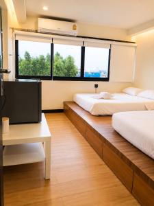 two beds in a room with a tv and a desk at Sukhum Ratchada Sutthisan in Bangkok