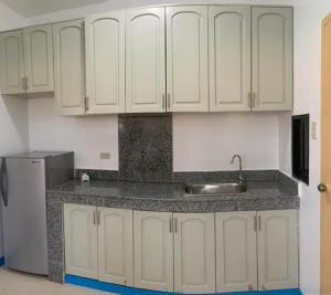 a kitchen with white cabinets and a sink and a refrigerator at Nassim Hotel and Beach Resort in Casagan