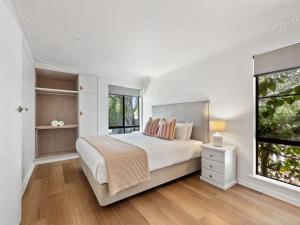 a white bedroom with a large bed and a window at Bluewater Retreat - Pet-Friendly Coastal Oasis in Broadwater