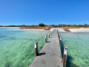 a pier stretches out into the water near a beach at Bluewater Retreat - Pet-Friendly Coastal Oasis in Broadwater