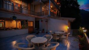 a patio with two tables and chairs and a balcony at Echor Mountain Crest Jibhi in Jibhi