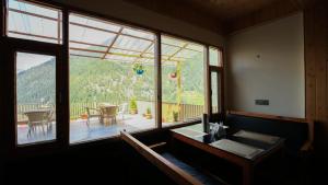a room with a large window with a table and chairs at Echor Mountain Crest Jibhi in Jibhi