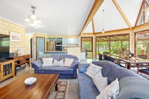 a living room with a blue couch and a table at Eagle Bay Beach Lodge - Escape to Coastal Serenity in Dunsborough +31 photos