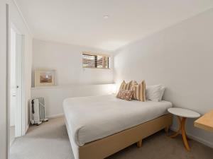 a white bedroom with a bed and a table at Rosella - Secluded Bushland Escape with Valley Views in Yallingup