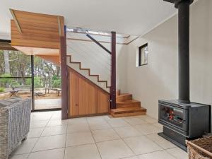 a living room with a wood stove and a staircase at Rosella - Secluded Bushland Escape with Valley Views in Yallingup