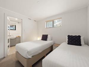 two beds in a white room with a sink at Rosella - Secluded Bushland Escape with Valley Views in Yallingup