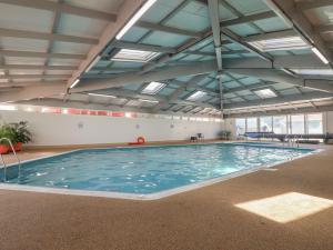 a large swimming pool with blue water in a building at Lodge 23 in Torpoint
