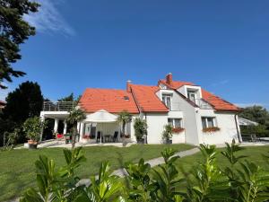a large white house with a red roof at Villa Palma Balatonboglár in Balatonboglár