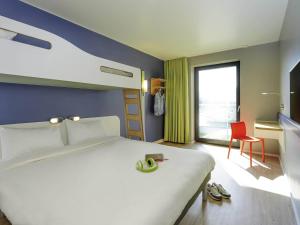a bedroom with a large white bed and a red chair at ibis budget Konstanz in Konstanz