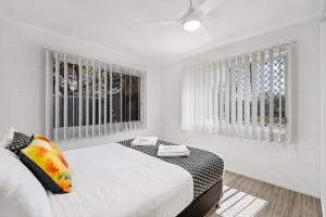 a white bedroom with two beds and a window at Quiet & Comfortable with Wi-fi in Andergrove