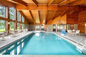 a swimming pool with tables and chairs in a building at AmericInn by Wyndham Hutchinson in Hutchinson