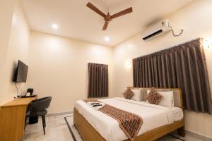 a bedroom with a bed and a desk and a television at Hotel SSV Suites Premium Near HItech City, Madhapur in Hyderabad
