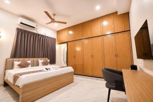 a bedroom with a bed and a desk with a chair at Hotel SSV Suites Premium Near HItech City, Madhapur in Hyderabad