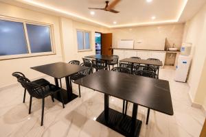 a dining room with tables and chairs and a kitchen at Hotel SSV Suites Premium Near HItech City, Madhapur in Hyderabad