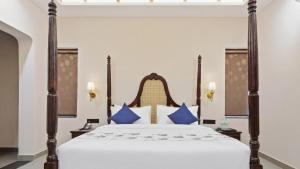 a bedroom with a large bed with blue pillows at Aamba Bagh Resort Kumbhalgarh in Kumbhalgarh