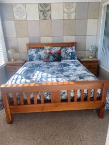 a bedroom with a wooden bed with a blue comforter at Fantail at Bluestone Retreat in Leeston