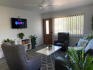 a living room with a couch and chairs and a tv at Ocean Breezes with Leafy View with Wi-fi in Slade Point