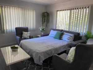 a bedroom with a bed and two chairs and a couch at Ocean Breezes with Leafy View with Wi-fi in Slade Point