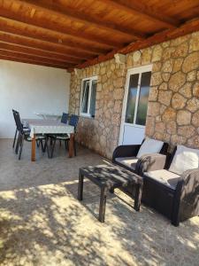 a patio with a table and chairs and a stone wall at Apartments Berti in Sveta Nedelja