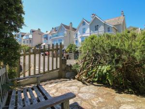 a wooden bench sitting next to a fence with houses at Waders in Salcombe