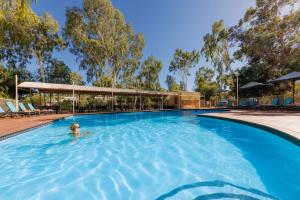 a person swimming in a large swimming pool at Outback Lodge in Ayers Rock