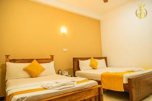 two beds in a room with yellow walls at Anoo Garden Villa in Trincomalee +63 photos