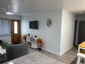 a living room with a couch and a tv on a wall at Seaside Breezes with Wi-fi in Slade Point