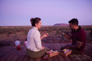 a man and woman sitting on a deck with boxes of food at Outback Lodge in Ayers Rock