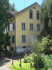 a yellow house with a fence in front of it at BnB villaSteiner in Birrwil