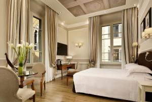 a bedroom with a white bed and a desk and a table at FH55 Hotel Calzaiuoli in Florence
