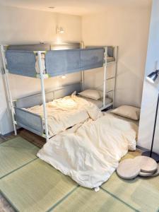 a bedroom with two bunk beds with towels on the floor at Maison Stay Kobe in Kobe