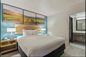 a bedroom with a bed with a painting on the wall at Days Inn Merced / Yosemite Area in Merced
