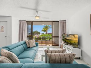 a living room with a blue couch and a tv at Alexandria Apartments in Alexandra Headland