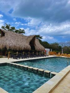 a resort swimming pool with chairs and a thatched roof at Oasis Manzanillo Del Mar in Manzanillo del Mar