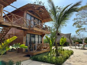 a wooden house with a palm tree in front of it at Oasis Manzanillo Del Mar in Manzanillo del Mar