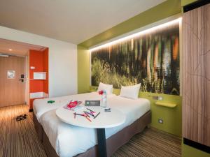 a hotel room with a large bed with a table at Ibis Styles Toulouse Labège in Labège