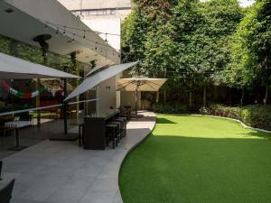 a garden with green grass and tables and umbrellas at Ibis Mexico Alameda in Mexico City