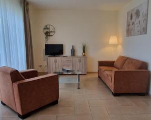 a living room with two couches and a tv at Hotel Garni Am Lindenhof Bunde in Bunde