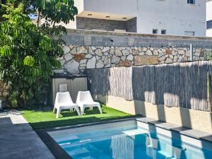 two white chairs sitting next to a swimming pool at המקום של אסי - Assi's place in Oshrat
