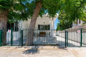 a green fence in front of a house with trees at Arty Haven - Spacious 3-BR House in Larnaca in Larnaca