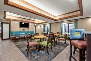 a waiting room with tables and chairs and a tv at La Quinta by Wyndham Midwest City - Tinker AFB in Midwest City