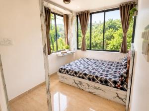 a bedroom with a bed in a room with windows at LuxeBnb - Hill View 2bhk Baner in Pune