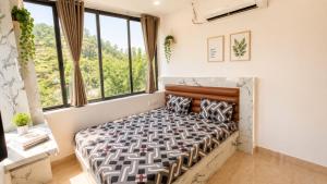 a bedroom with a bed and large windows at LuxeBnb - Hill View 2bhk Baner in Pune