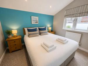 a bedroom with a large white bed with a blue wall at Seaside Escape in Westward Ho! 3-Bed Family Holiday Home with Sea Views in Westward Ho