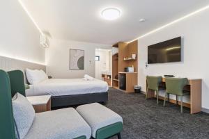 a hotel room with two beds and a table and a couch at Frankston Bay Motel in Frankston